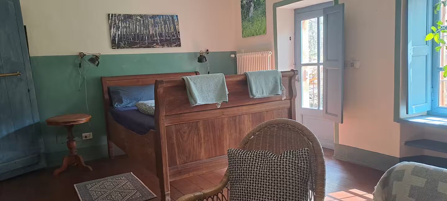 Camera da letto con testiera color petrolio e poltrona in vimini